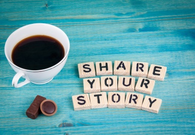 share your story. Coffee mug and wooden letters on wooden background.